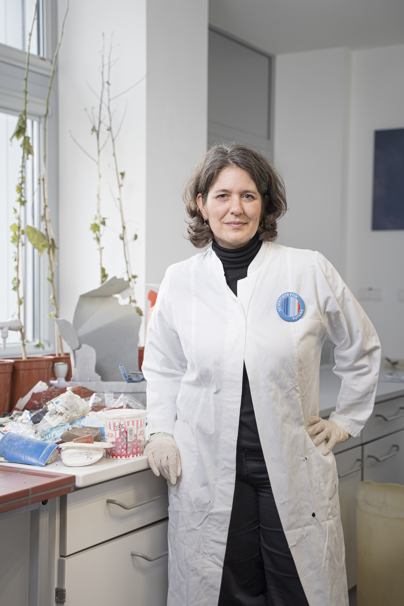 Wissenschaftlerin Melanie Bergmann in weißem Kittel vor einer Ablage mit Plastikmüll