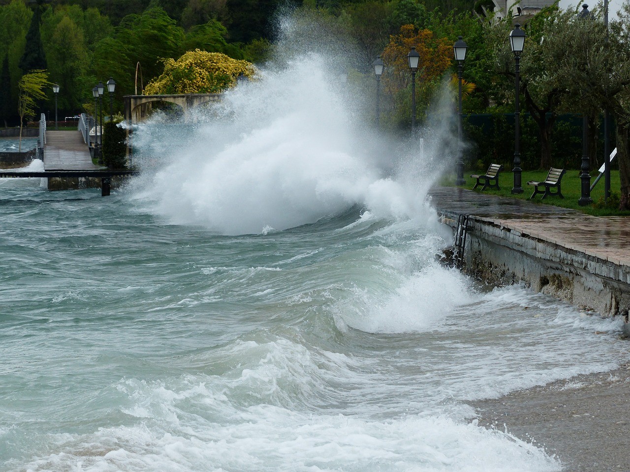 Eine große Welle schlägt gegen eine Uferpromenade