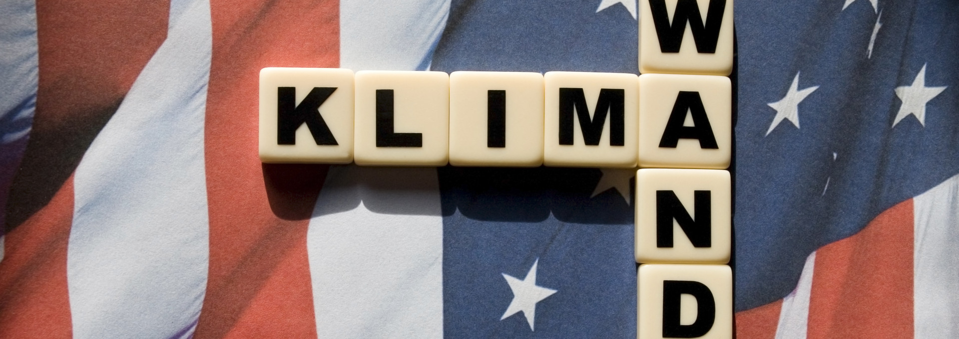 Amerikanische Flagge auf der in Buchstabenwürfel das Wort "Klimawandel" steht