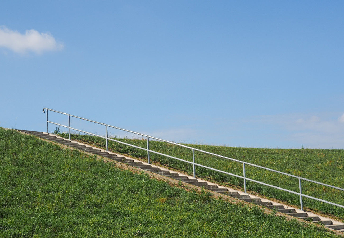 Eine Treppe führt auf einen Deich hinauf
