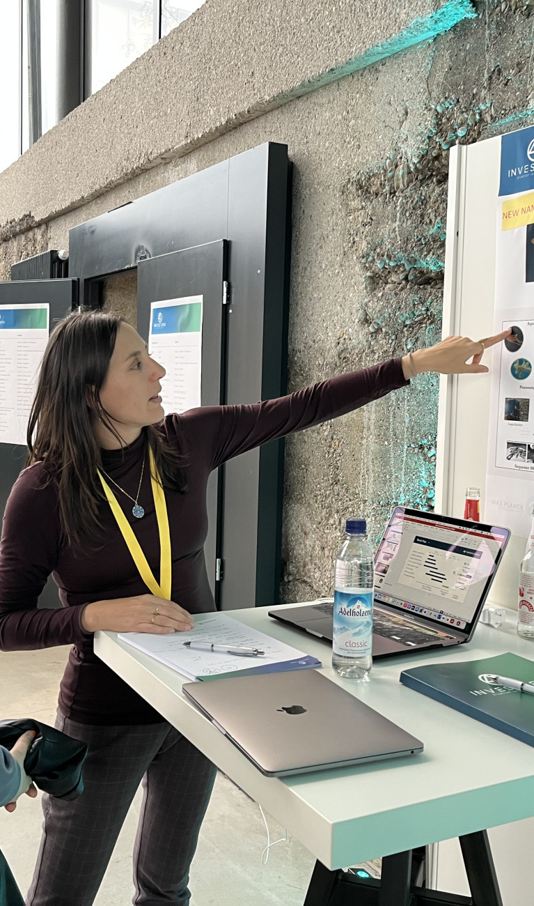 Eine Expertin erklärt Makroalgen anhand eines Posters.