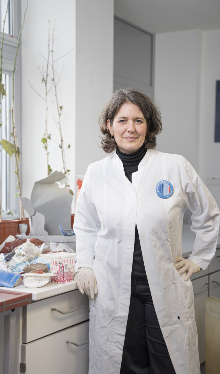Wissenschaftlerin Melanie Bergmann in weißem Kittel vor einer Ablage mit Plastikmüll