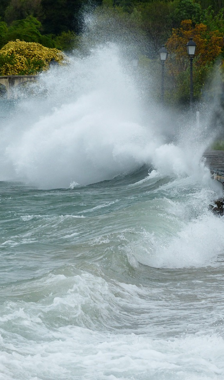 Eine große Welle schlägt gegen eine Uferpromenade