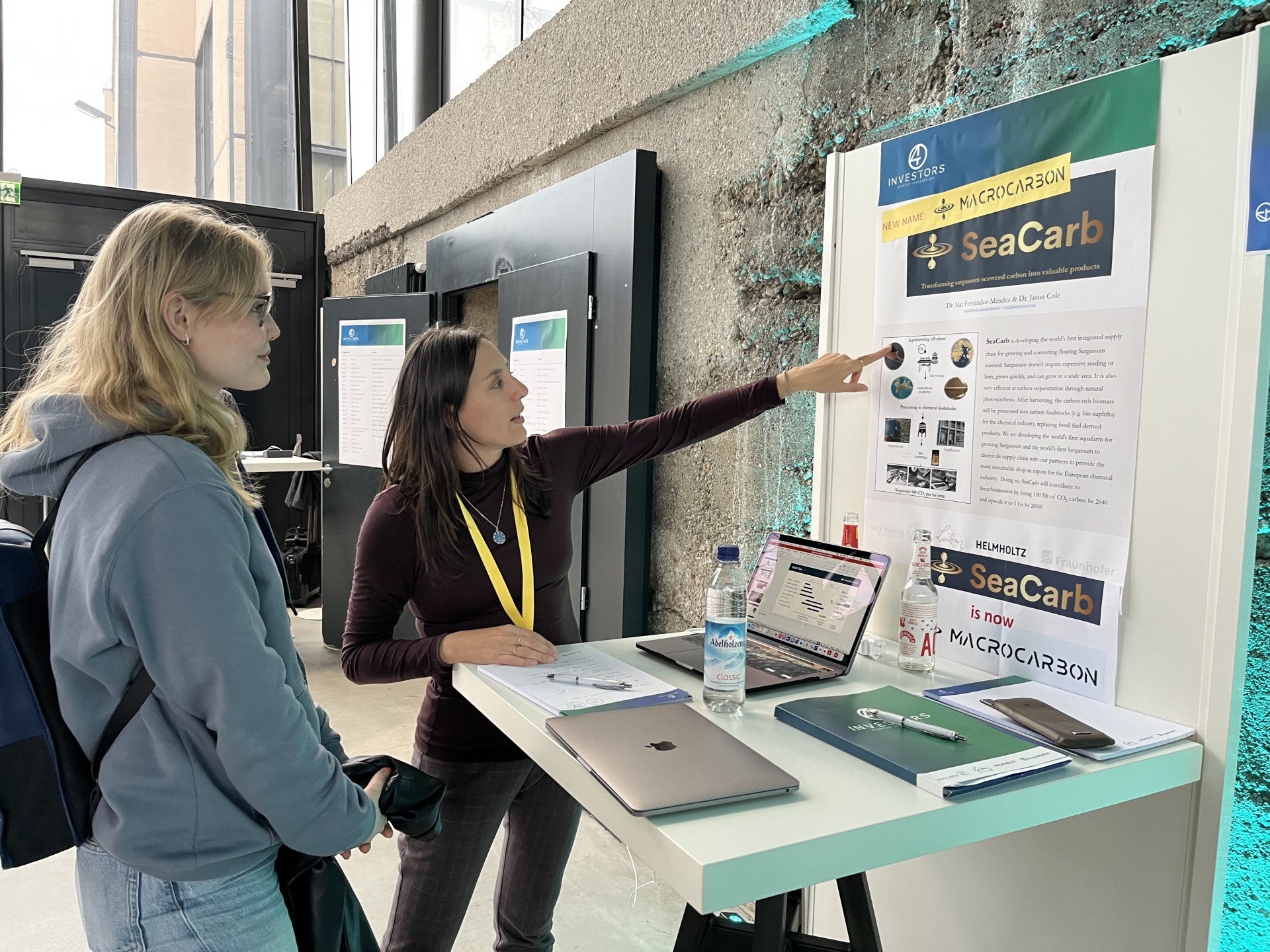 Eine Expertin erklärt Makroalgen anhand eines Posters.