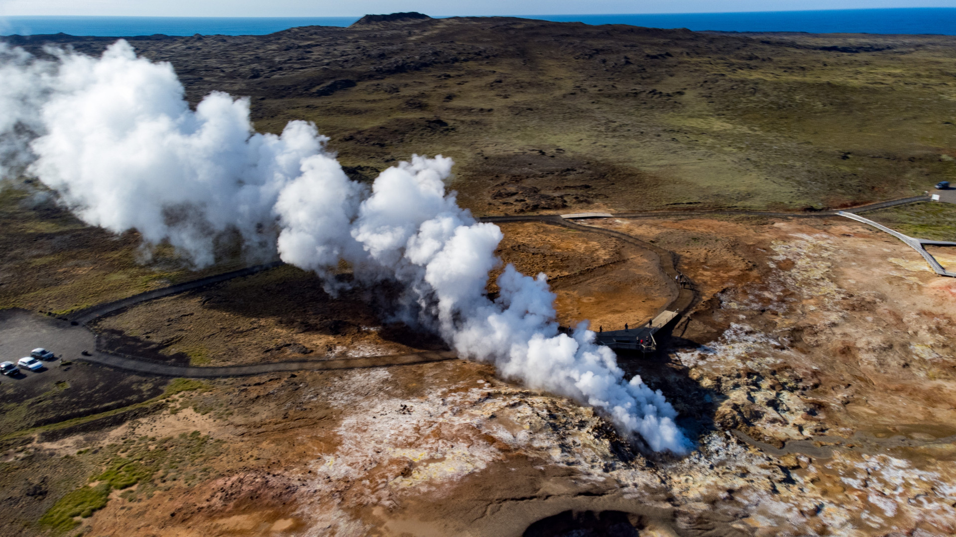 Luftaufnahme eines geothermischen Gebiets in Island mit Dampfquellen und heißen Quellen, umgeben von farbenprächtiger Minerallandschaft