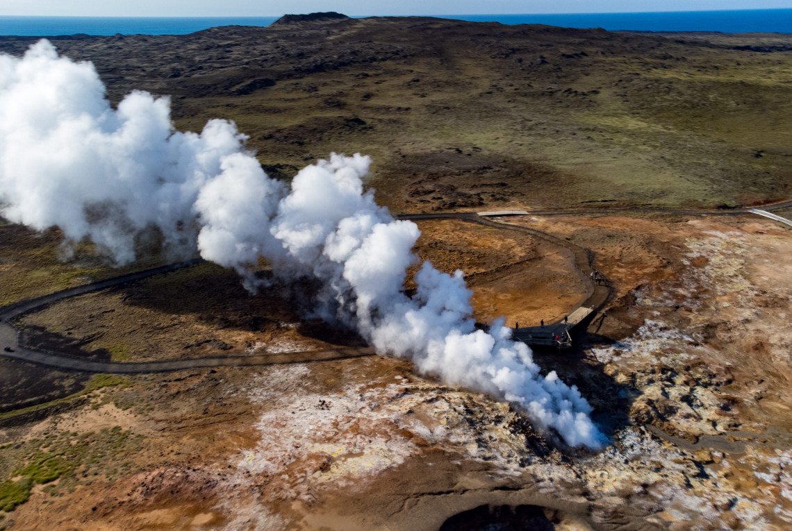 Luftaufnahme eines geothermischen Gebiets in Island mit Dampfquellen und heißen Quellen, umgeben von farbenprächtiger Minerallandschaft