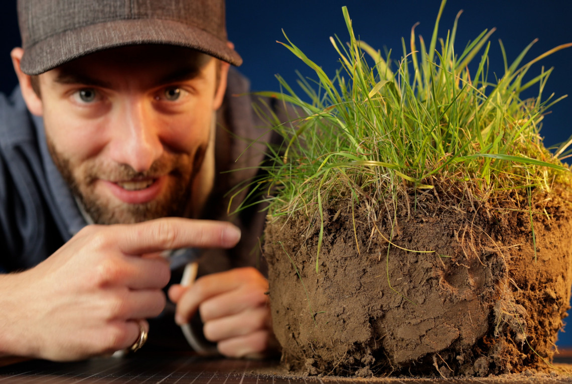 Standbild aus dem Film: Unser YouTuber mit einem ausgestochenen Stück Boden, wo oben das Gras rauswächst.