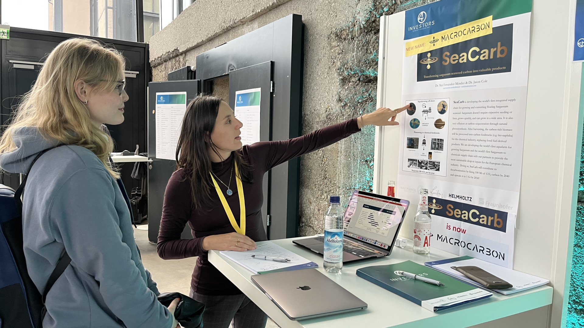 Eine Expertin erklärt Makroalgen anhand eines Posters.